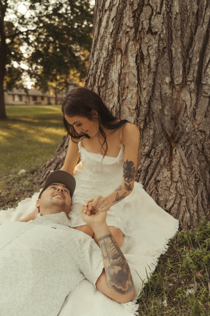 Man laying in fiance's lap looks up at her adoringly during White Bear Lake engagement photoshoot.