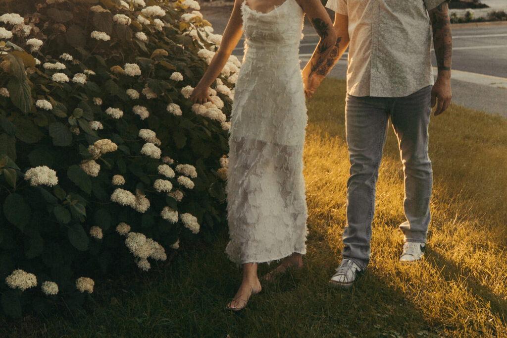 Man and woman walk hand in hand by the hydrangeas.