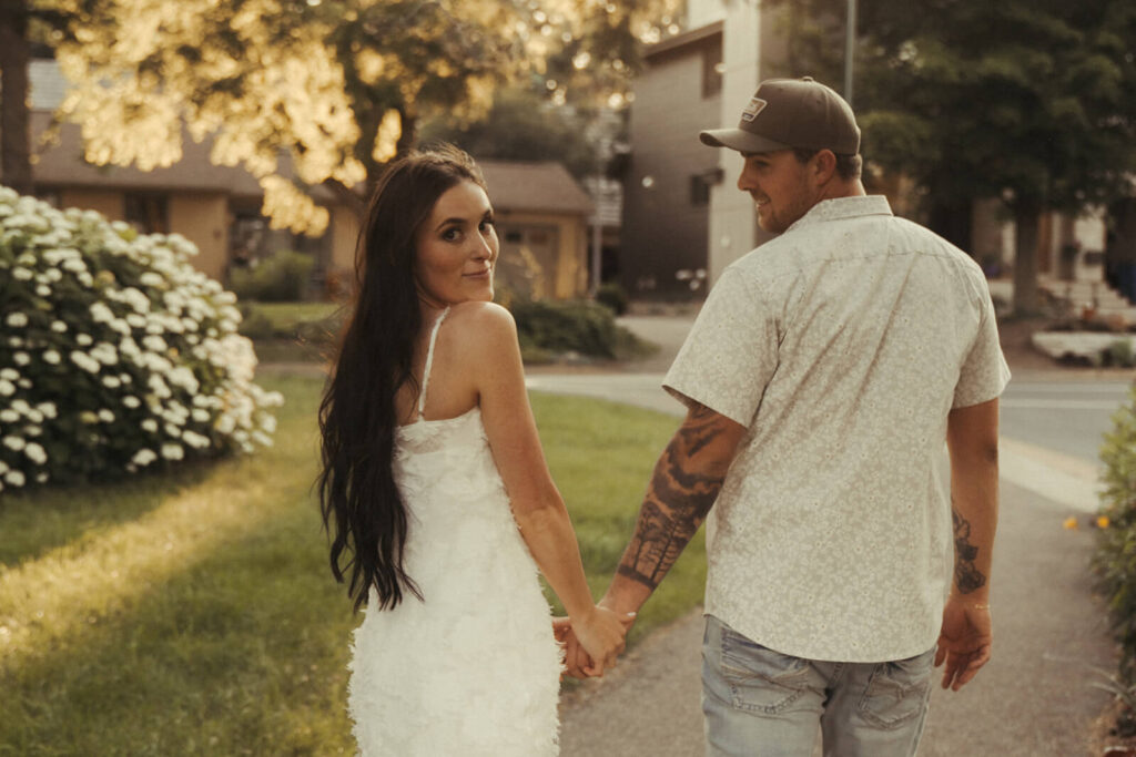 Engaged couple walks hand in hand down the park path in White Bear Lake.