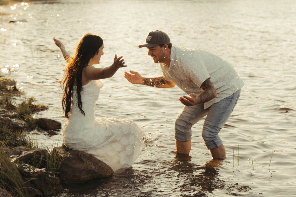 Engaged couple splashes water at each other in White Bear Lake, Minnesota.