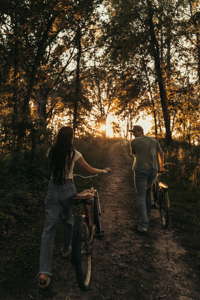 Man and woman wheel their bikes off into the sunset.