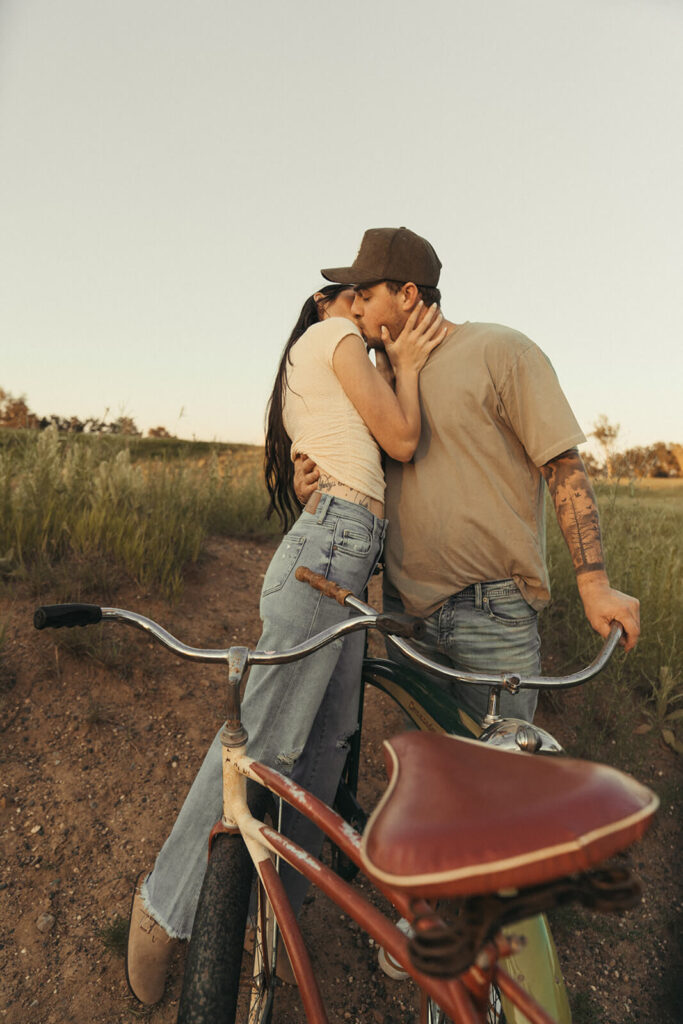 Engaged couple kisses as man holds onto bike in White Bear Lake, Minnesota.