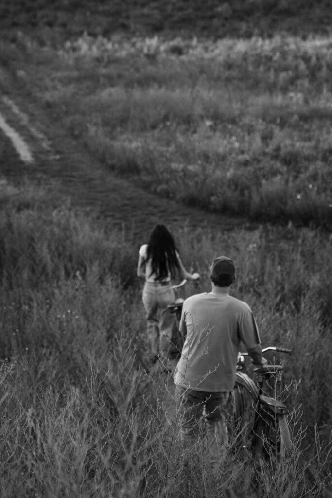 Engaged couple wheels their bikes down the hill in White Bear Lake, Minnesota.