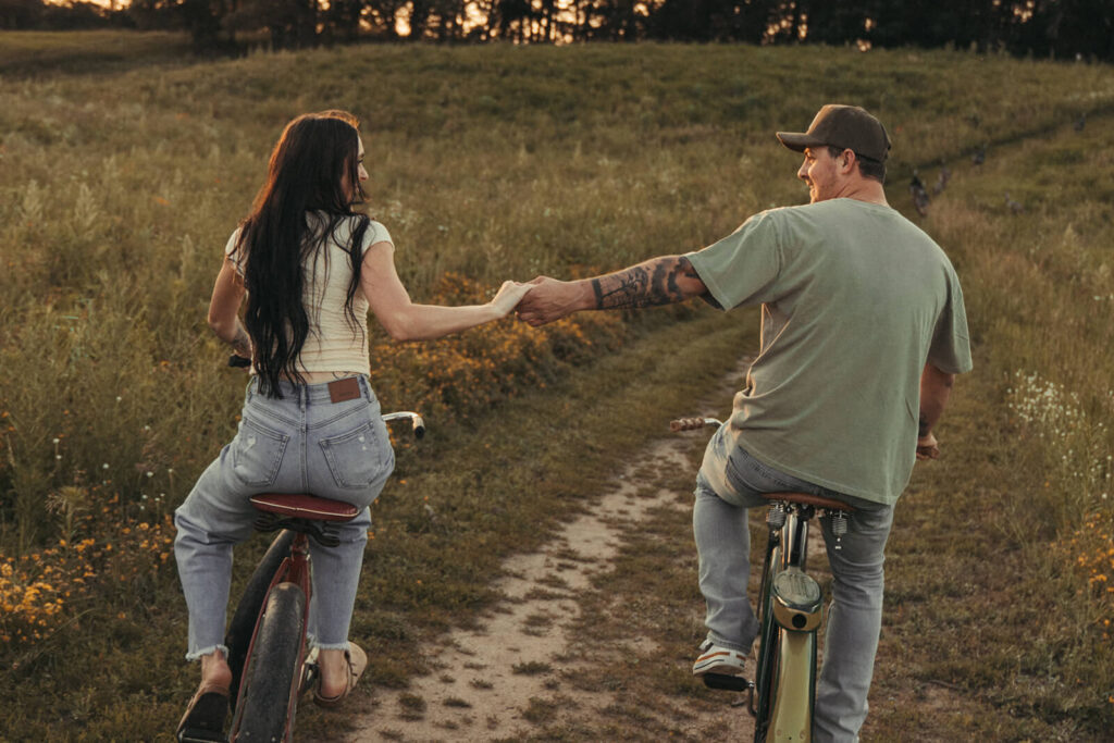 Engaged couple bikes hand in hand through White Bear Lake, Minnesota.