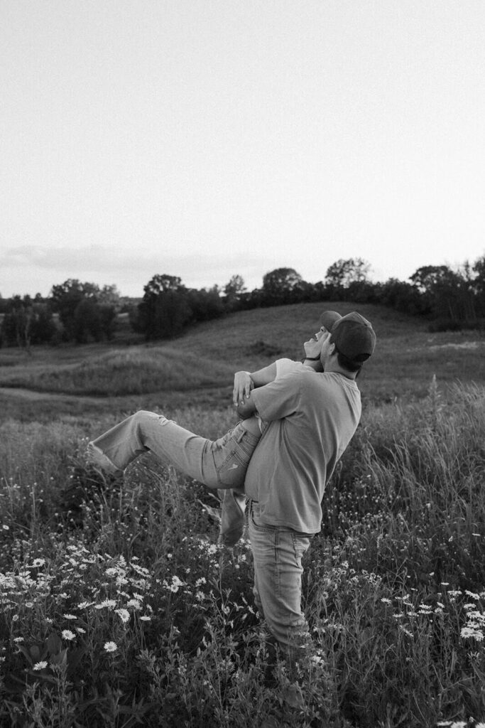 Man twirls his fiance through the air in Minnesota meadow.
