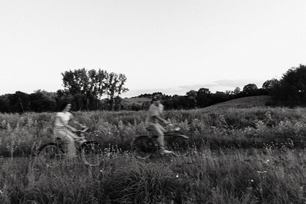 Man and woman go on a date night riding bikes through Minnesota meadow.