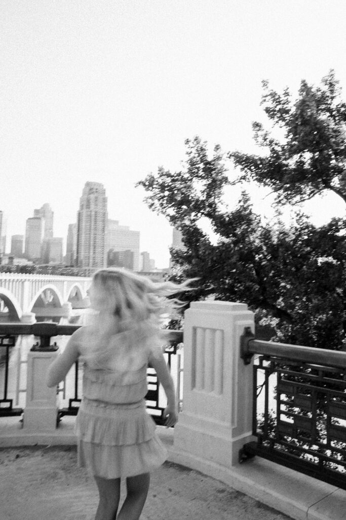 High school girl twirls on ledge overlooking Minneapolis city skyline