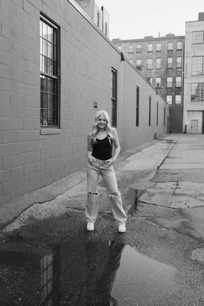 Girl stands with hands in her jean pockets in urban setting of downtown Minneapolis