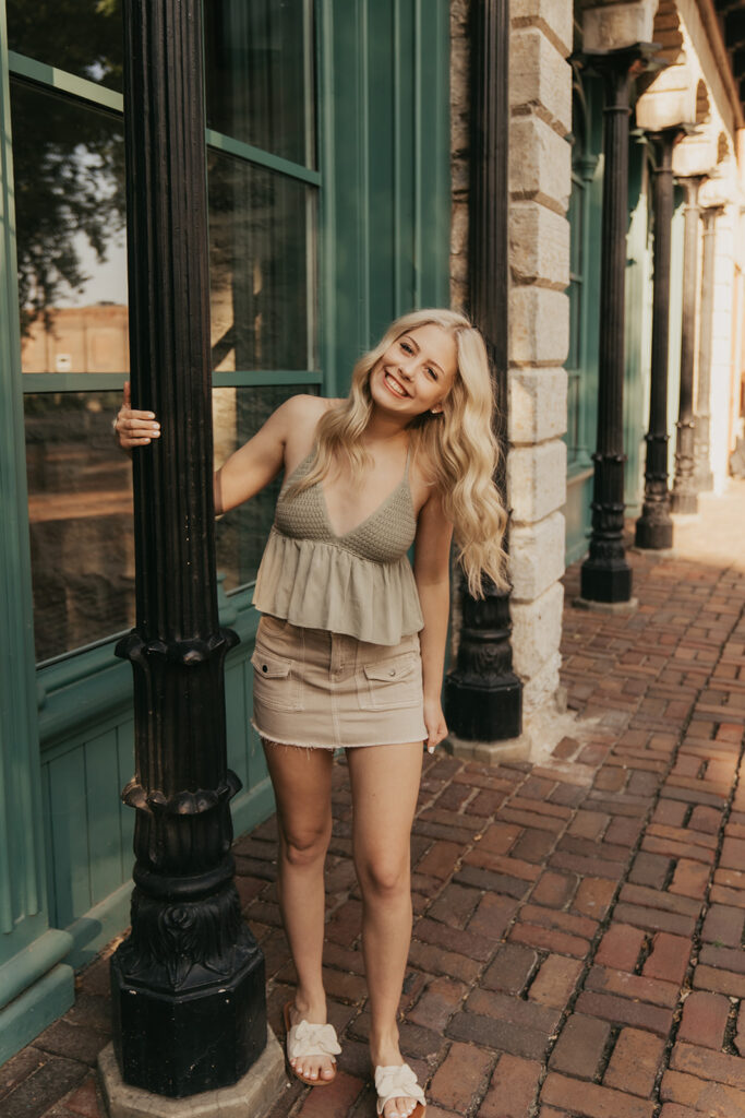 High school senior photos Minneapolis with girl twirling around lamppost in St. Anthony Main