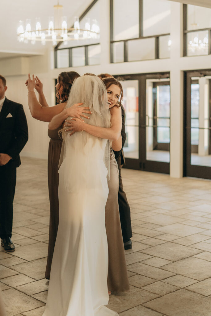 Bride embraces bridesmaids during a joyful pre-ceremony moment inside Equestria West’s bright atrium.