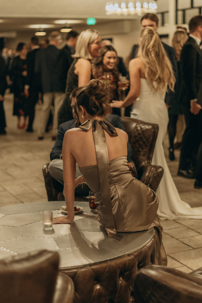 Guests mingling during cocktail hour in the lounge space at Equestria West — moody lighting and satin dresses on full display.