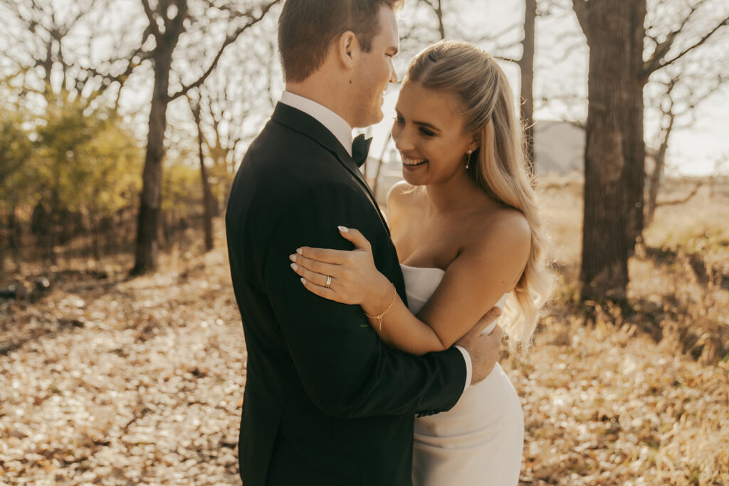 Bride and groom holding each other and laughing in the woods — a candid, joyful moment from their late fall wedding in Chaska.