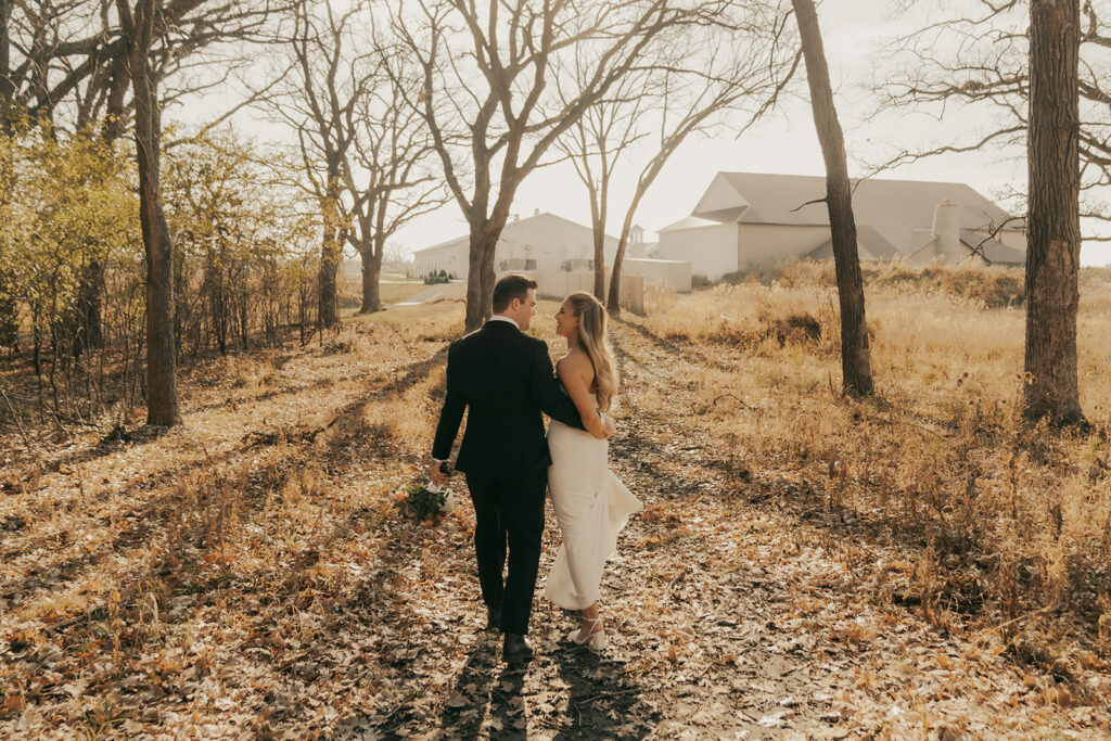 The couple walks hand in hand down a leaf-strewn path near Equestria West, soaking in the late autumn sun in Chaska, Minnesota.