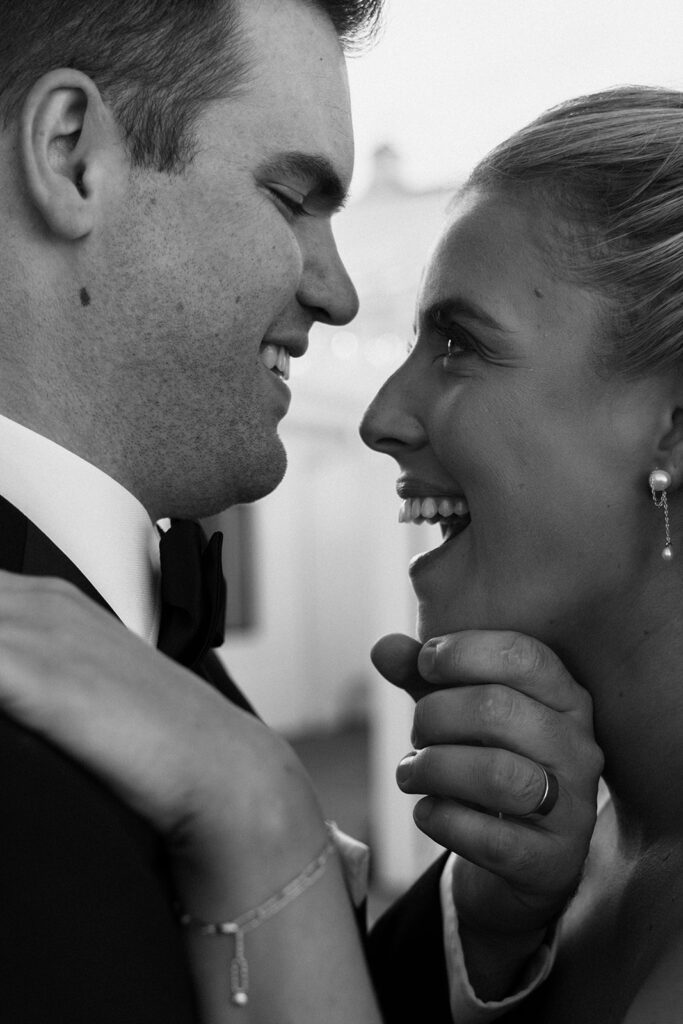 Close-up of the couple smiling at each other, framed in black and white — candid joy after their candlelit vows at Equestria West.