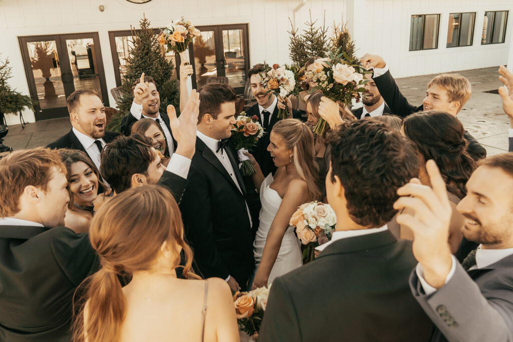 The couple surrounded by their joyful wedding party during golden hour outside a venue in Chaska, Minnesota.