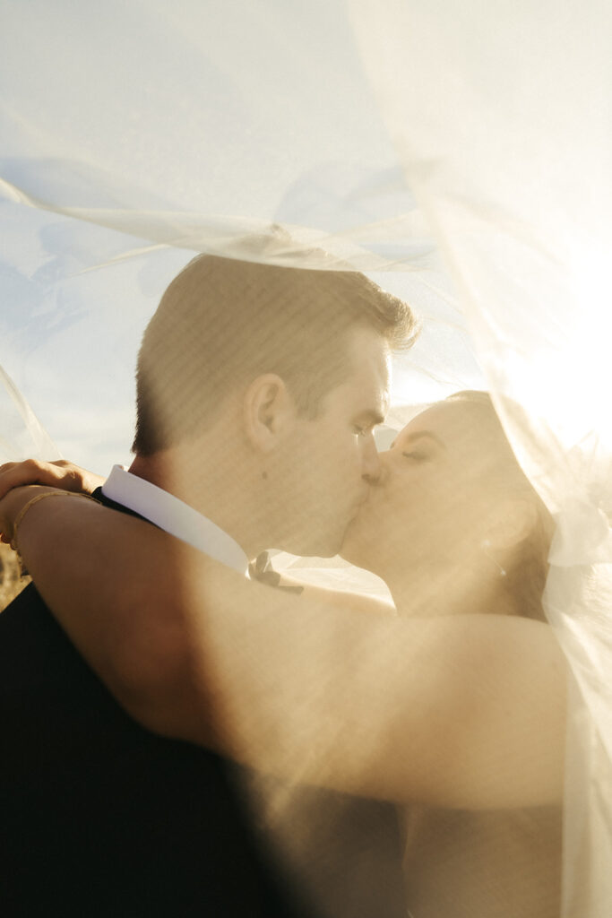 The couple sharing a golden-hour kiss beneath the bride’s veil during their romantic candlelit November wedding in Chaska, Minnesota.