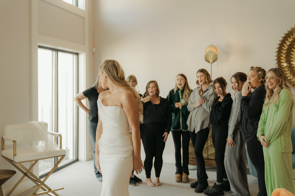 Bridesmaids reacting with joy and awe during the bride’s dress reveal before the candlelit ceremony at Equestria West.