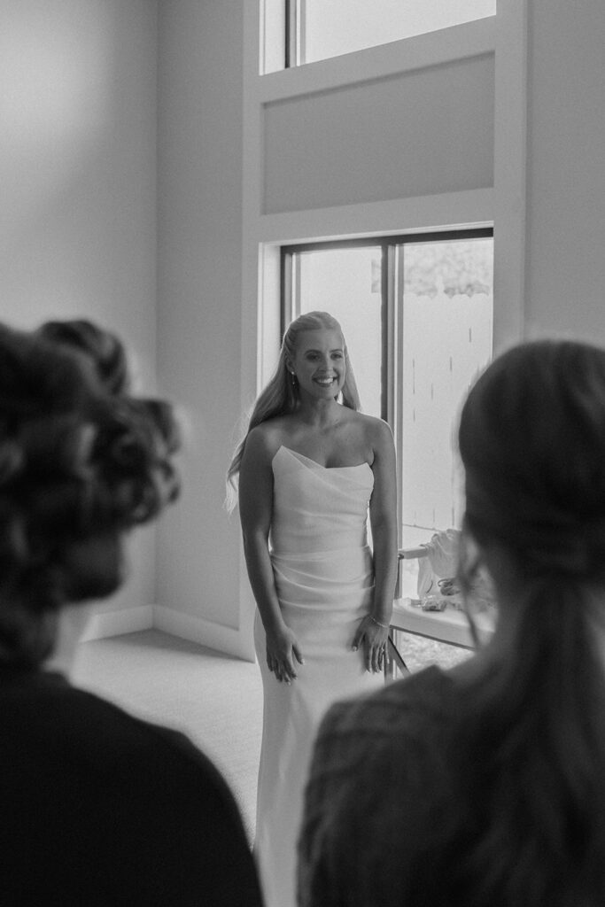 The bride smiling at her bridesmaids just before getting into her gown on the morning of her November wedding in Chaska.