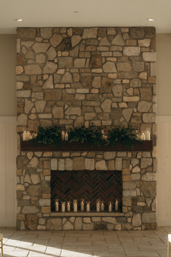 Close-up of the ceremony fireplace at Equestria West, decorated with glowing candles and fresh greenery for a romantic candlelit backdrop.