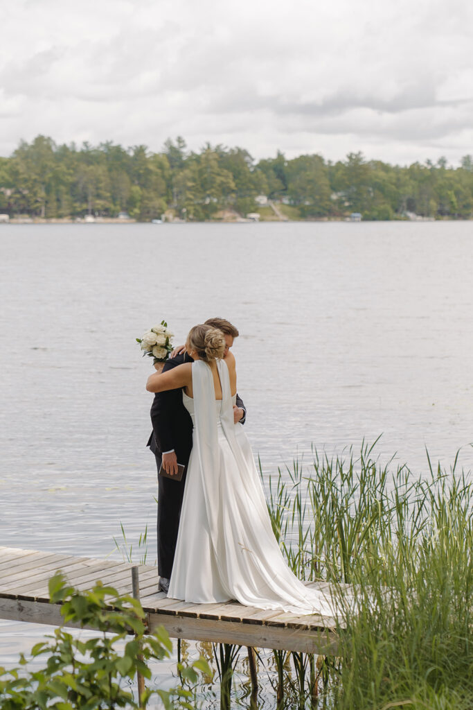 Bride hugs groom as they stand on the dock exchanging their emotional private vows