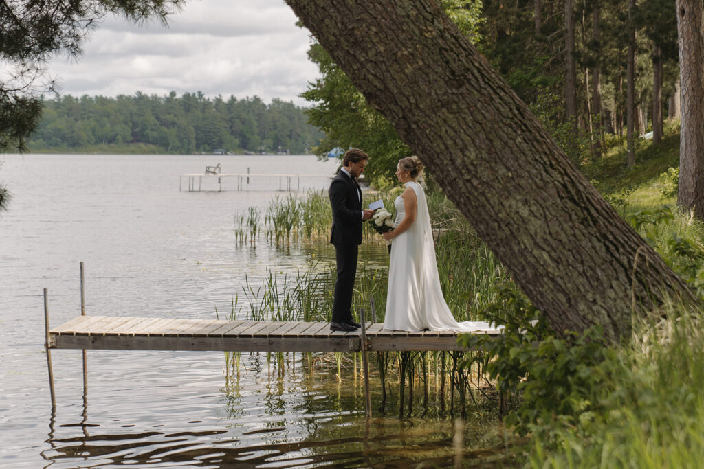 Bride and groom share intimate private vows on the dock at Catalyst by Nature Link in Minnesota