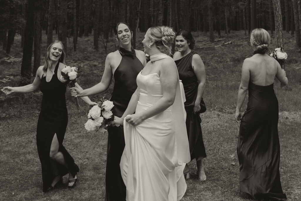 Bridesmaids dance around bride as she looks over her shoulder and laughs