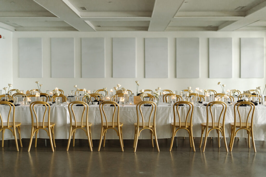 Harvest tables with bistro chairs in bright wedding reception space