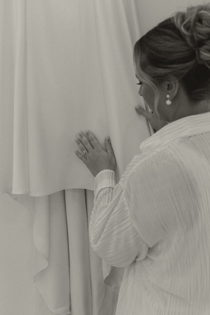 Timeless wedding photos of bride touching wedding dress as she gets ready for her morning
