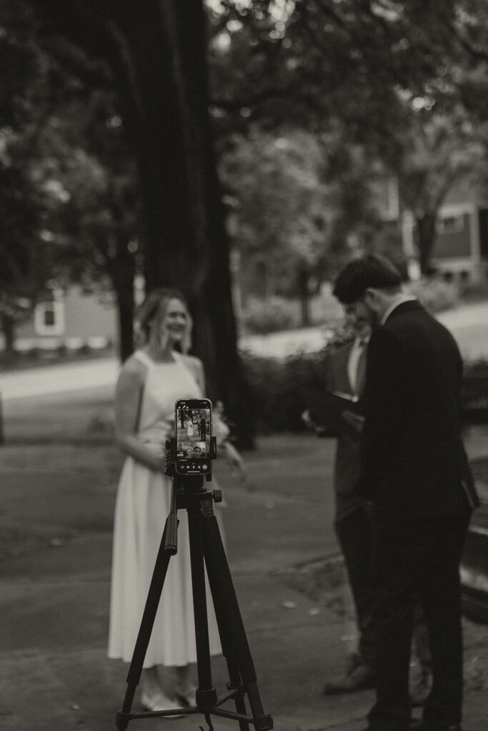 Bride and groom standing with a phone tripod for their livestreamed Irvine Park wedding.
