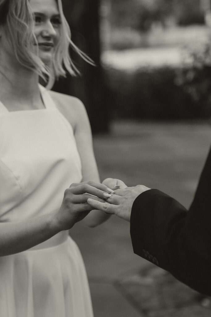 Bride places ring on groom’s finger during their Irvine Park wedding vows.