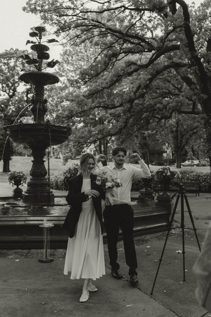 Couple cheering with the fountain behind them during this intimate Saint Paul Irvine Park wedding.
