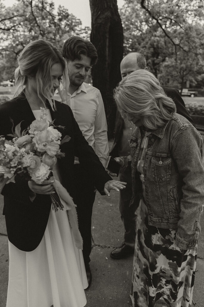 Bride showing groom's mom her wedding ring.