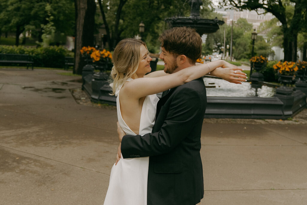 Couple embraces in front of the gothic fountain in Saint Paul for their Minnesota elopement.