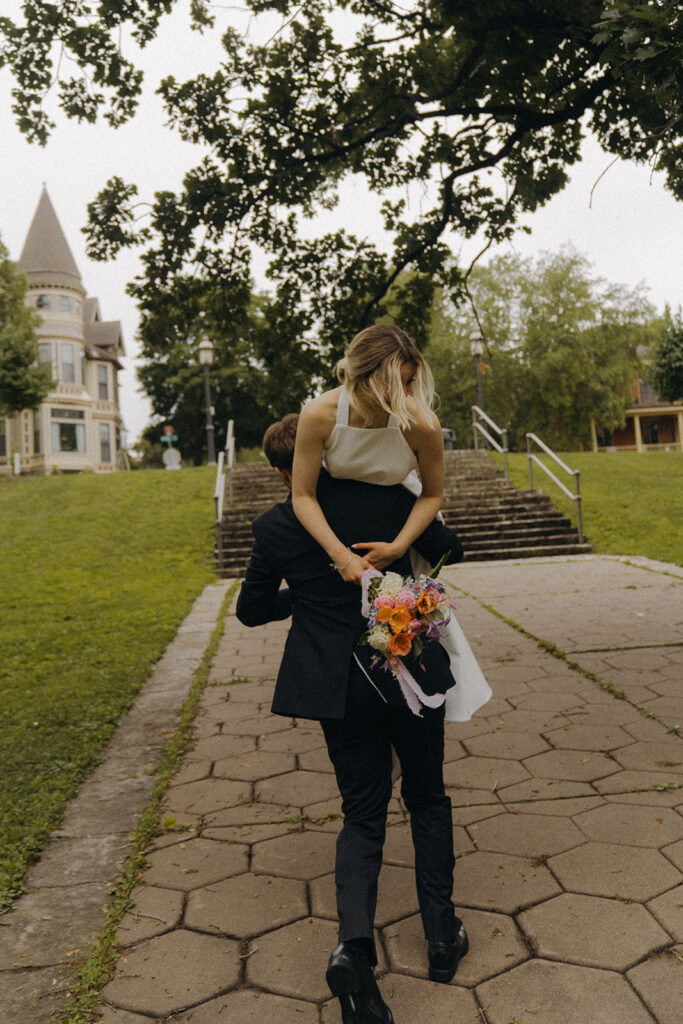 Groom twirls bride on the stone path for playful elopement photos at Irvine Park.