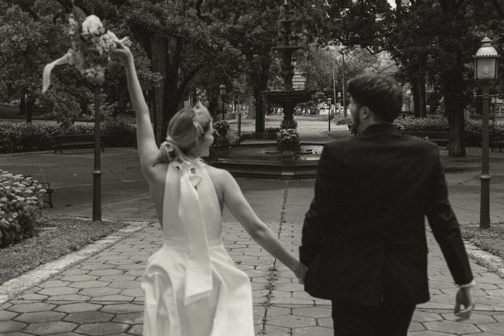 Bride throws bouquet in the air, walking hand in hand with the groom at their Irvine Park wedding.