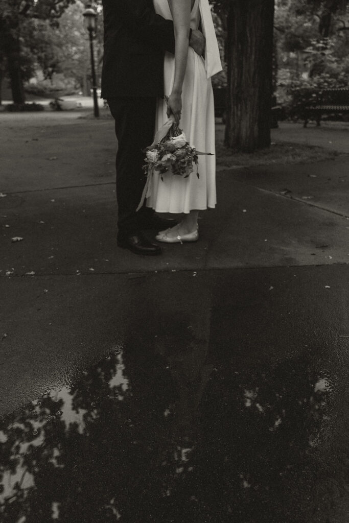 Black and white photo of the couple standing together in a puddle reflection at Irvine Park wedding.