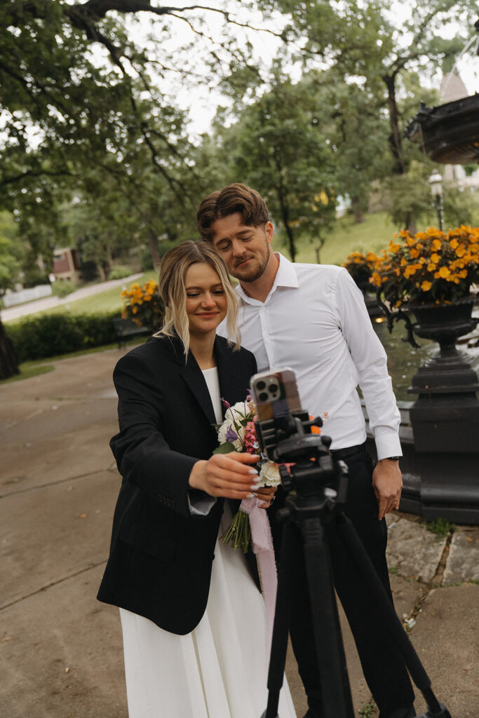 Bride and groom check the phone together, smiling during their livestreamed Minnesota elopement.