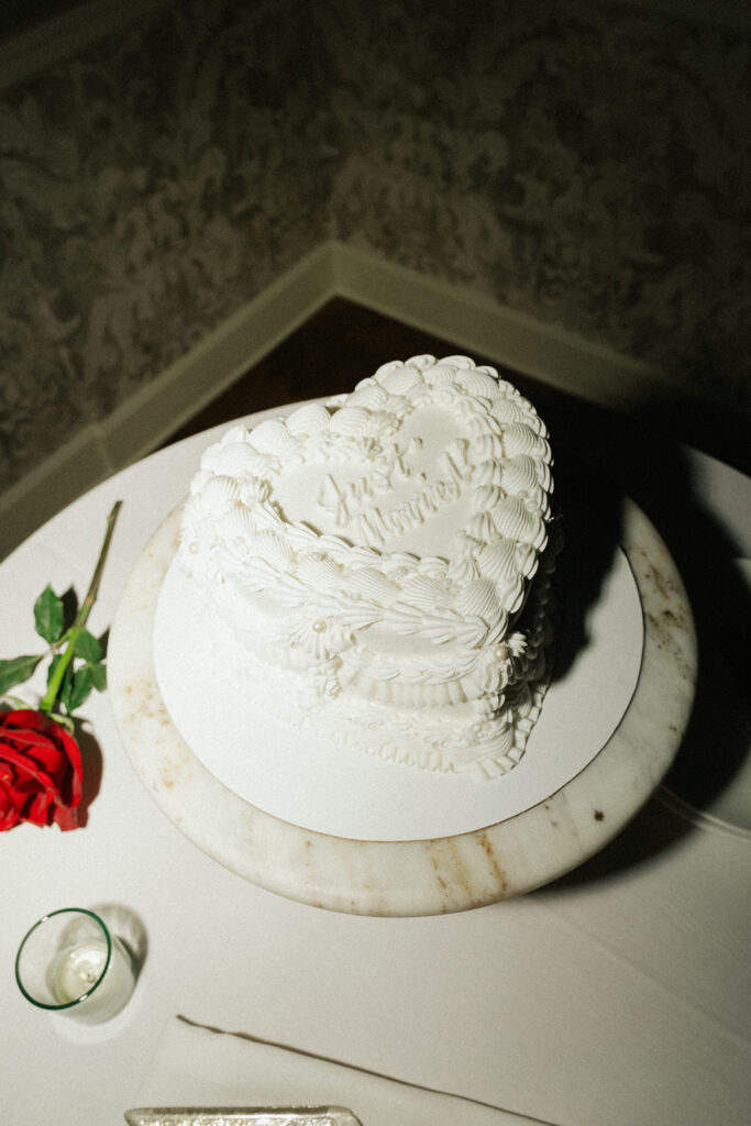 Heart-shaped vintage wedding cake with piped frosting and red roses at a classic St. Paul reception.