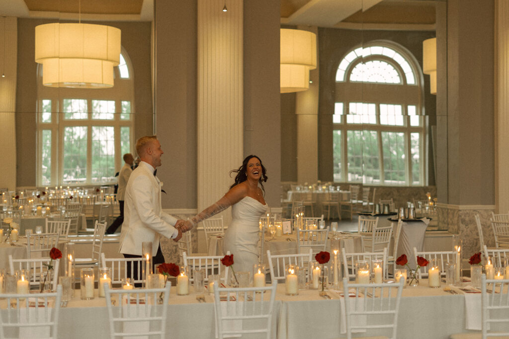 Couple holding hands and dancing between candlelit harvest tables during their classy wedding reception in Minnesota.