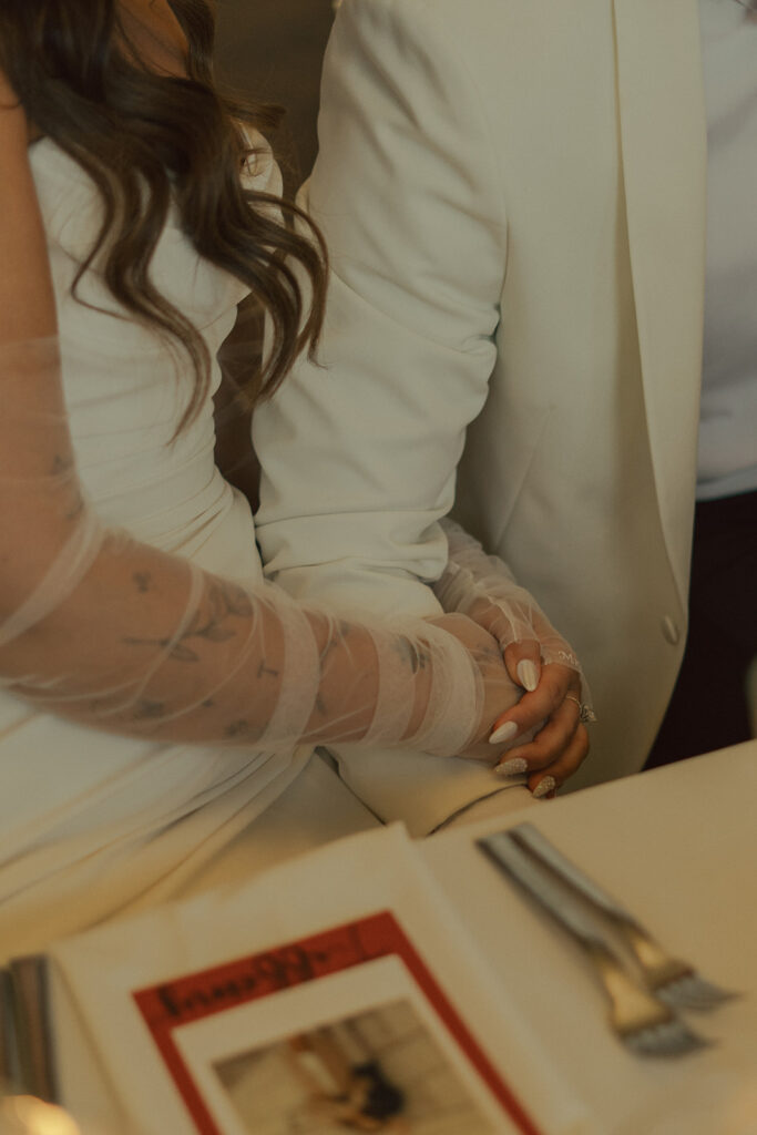 Bride resting her hand on the groom’s arm at a romantic candlelit table, captured with timeless wedding photography.