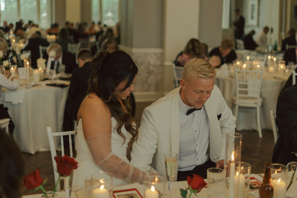 Bride and groom bowing their heads in prayer during intimate candlelit wedding reception in Twin Cities.
