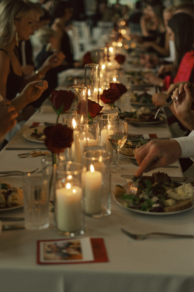 Candlelit tables with red roses and elegant décor at a classic Minnesota wedding reception.