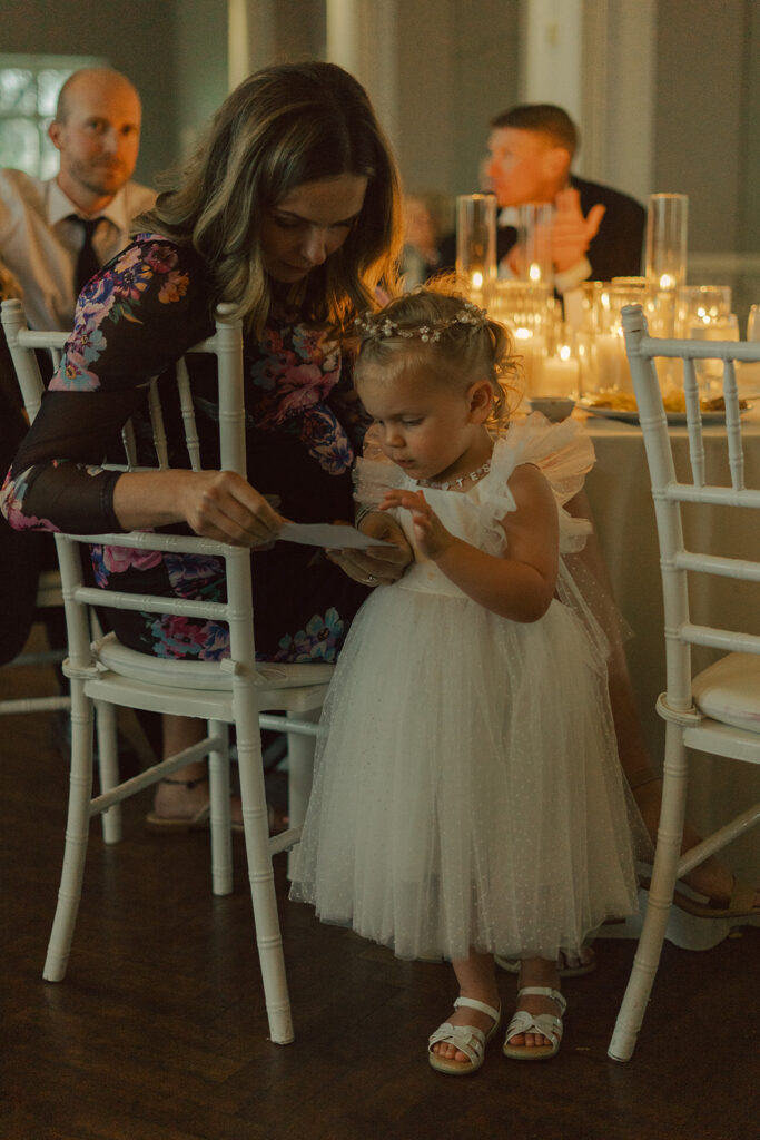 Little flower girl dancing beside the bride and groom during a family-style Minnesota wedding celebration.