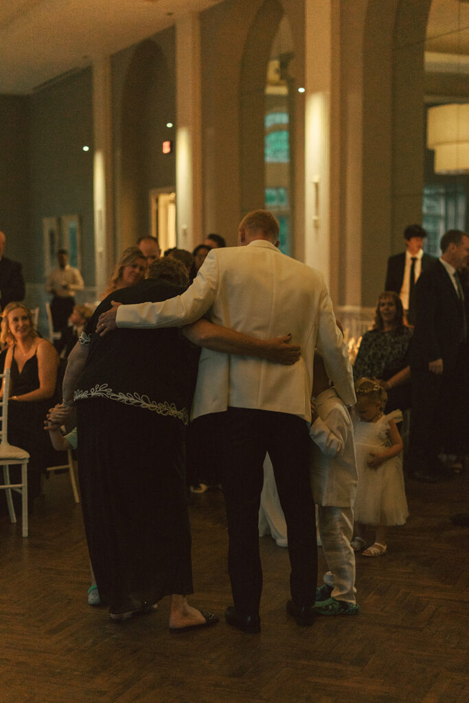 Family embracing during an emotional moment at a St. Paul wedding reception.