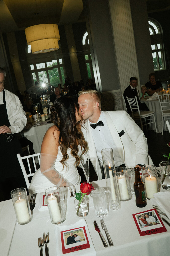 Bride and groom kissing during speeches at their timeless St. Paul wedding reception.
