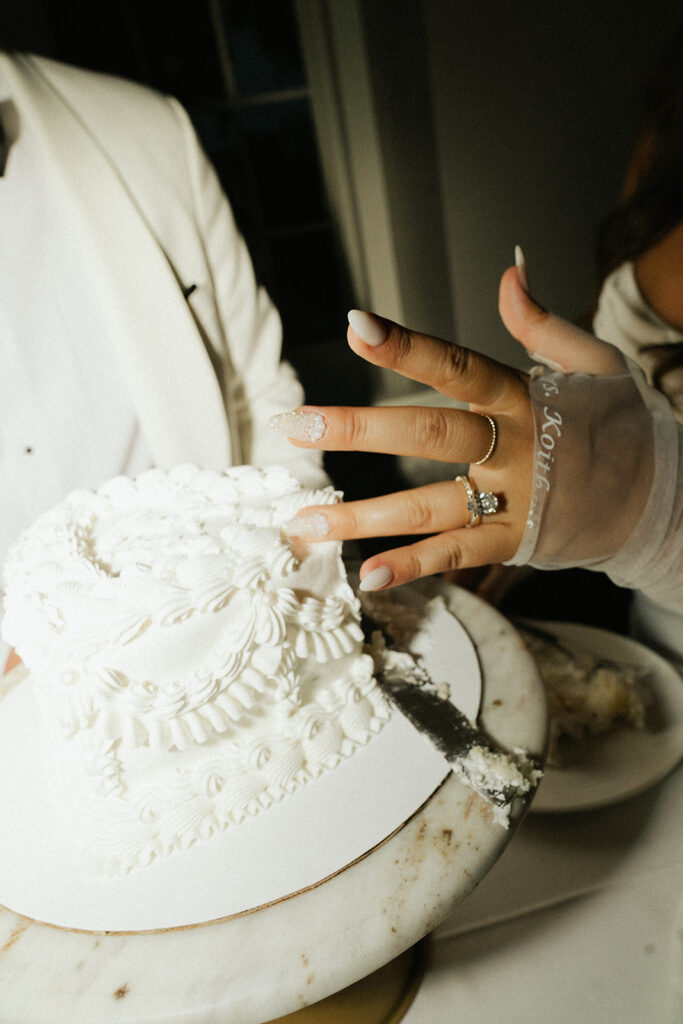 Bride showing her frosting-covered hand during a playful cake cutting moment at a Minnesota wedding.