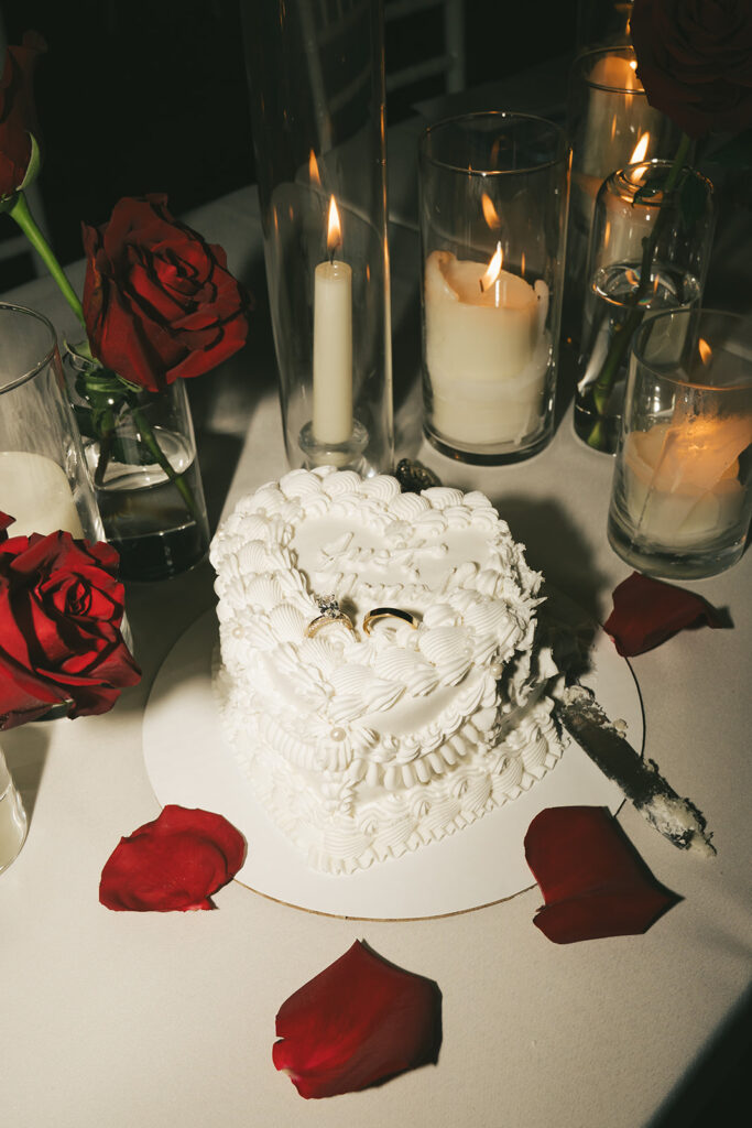 Heart-shaped vintage cake surrounded by red rose petals and candlelight at a classic wedding reception in St. Paul, Minnesota.