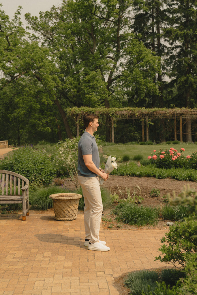 Joey standing in the garden at Noerenberg Gardens with a bouquet, waiting for Bella to arrive.