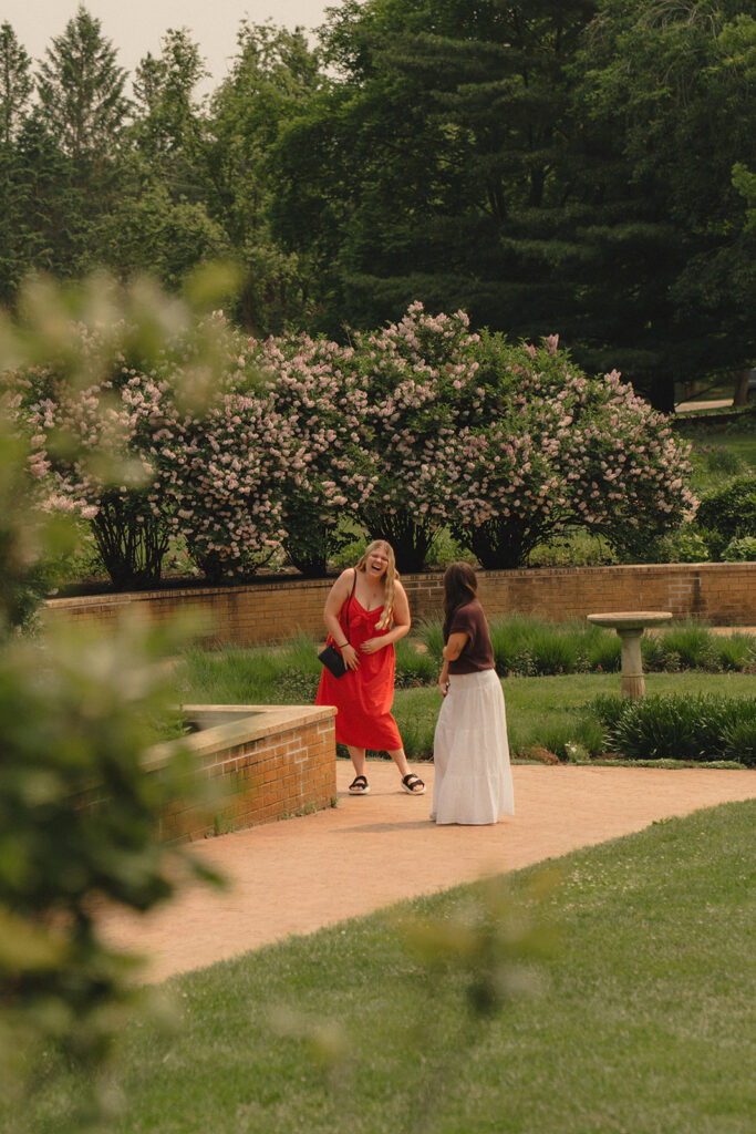 Bella walking toward her friend in the garden moments before the proposal, unaware of what’s coming.
