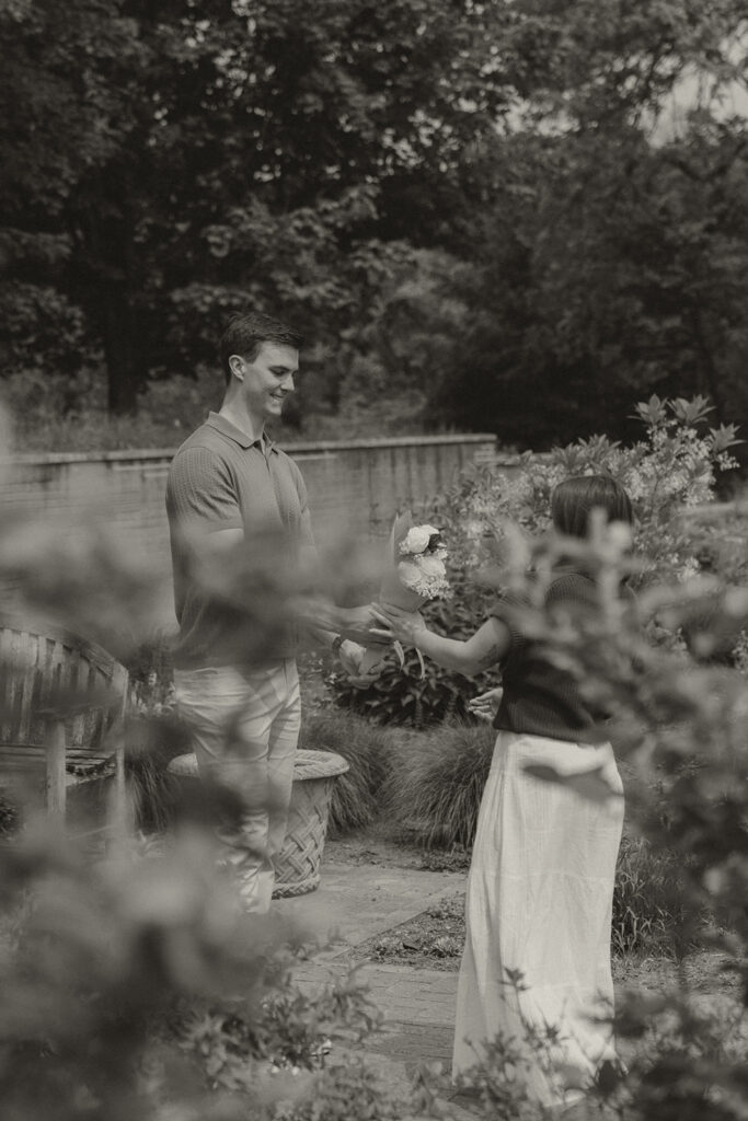 Bella walking toward Joey in the garden while he smiles, just seconds before the proposal.